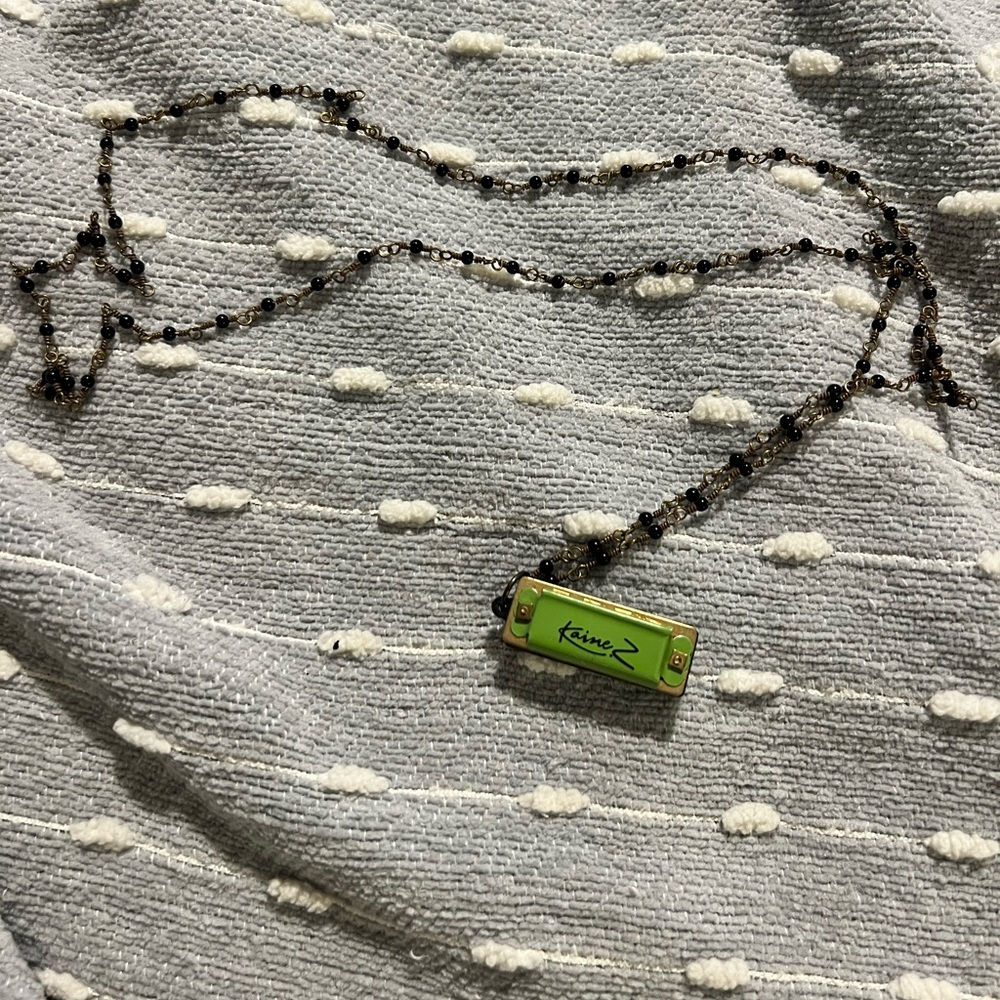 Z. Kaine necklace. 17”with green working harmonica, black beads, gold accents.